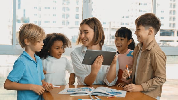 Smart teacher holding tablet while open online lesson to group of students. Skilled instructor explained engineering code lesson while young learner sitting and listening presentation. Erudition.