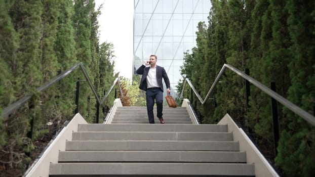 Caucasian businessman walking up stair and calling manager by using smart phone. Top view of manager talking marketing team and planning financial strategy by telephone while going up stair. Urbane.