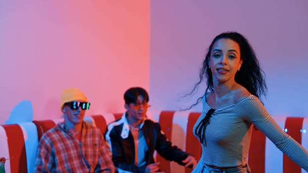 Hispanic dancer perform movement while diverse friend sitting and dancing together. Happy professional hipster moving hand while multicultural group supporting and encouraging friend. Regalement.