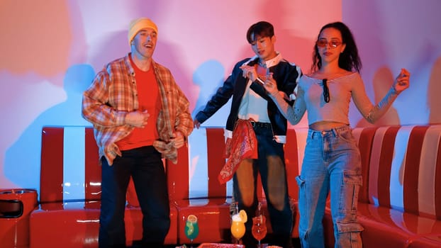 Diverse street dancer moving to city pop music at party with neon light while wearing hippie fashion. Attractive hipster perform or practicing dancing together while looking at camera. Regalement.