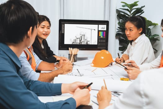 Diverse group of civil engineer and client working together on architectural project, reviewing construction plan and building blueprint at meeting table. Prudent