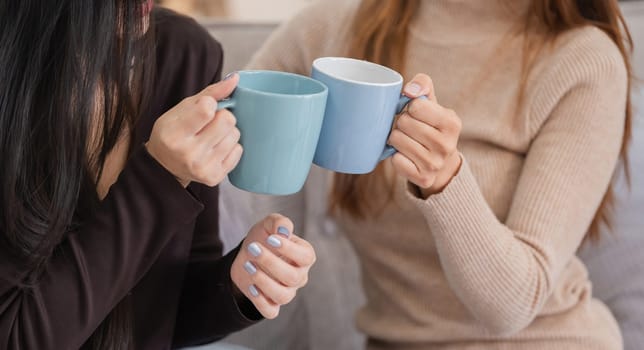 A loving lesbian couple sharing a warm moment while drinking hot tea together in a cozy home environment.