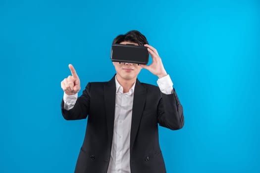 Asian businessman looking thorough VR while touching screen with connecting business world report in futuristic metaverse analyzing innovation technology virtual reality blue copyspace. Contrivance.