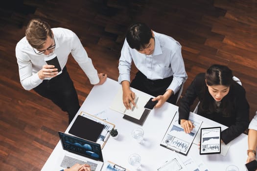 Top view analyst team utilizing BI Fintech to analyze financial data at table in meeting room. Analytic BI dashboard power on paper for business insight and strategic marketing planning. Prudent