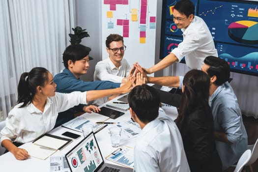 Analyst team leader celebrate and high five together with his colleague after successful data analysis meeting using FIntech software power with business intelligence or BI dashboard. Prudent