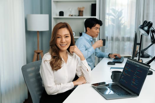 Profile smiling beautiful Asian businesswoman looking camera to portrait pose at modern office on working desk casual day. Blurry background man colleague analyzing data market plan on pc. Infobahn.