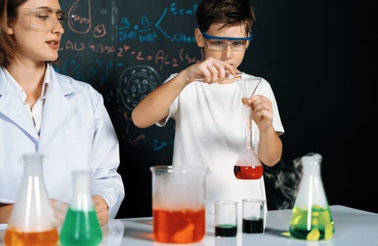 Teacher in support and watch student in laboratory they wear safety glasses, stand and experiment about science of chemistry in STEM class. Student funny do experiment with liquid in tube. Erudition.