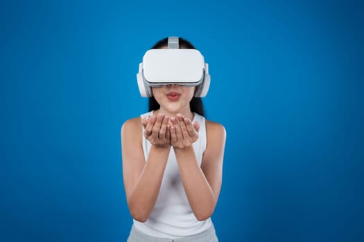 Smart female standing with blue background wearing VR headset connecting metaverse, futuristic cyberspace community technology. Elegant woman excited seeing generated virtual scenery. Hallucination.