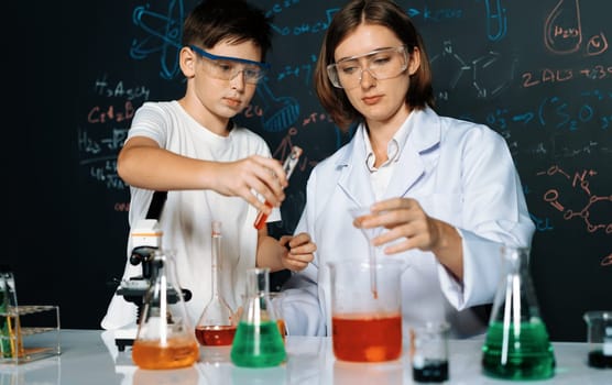 Teacher support schoolboy in laboratory. Schoolboy and teacher stand and experiment about science of chemistry in STEM class using liquid in glass container. Instructor mixing solution. Erudition.