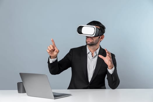 Skilled business man looking at data analysis while sitting at table with laptop and wearing VR glasses. Project manager working by using virtual reality system or connecting at metaverse. Deviation.