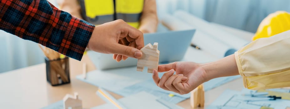 Professional engineer and architect collaborate on eco house project at meeting table with green design blueprint and architectural equipment at modern office. Focus on hand. Close up. Delineation.