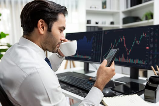 Trader businessman holding coffee cup focusing on dynamic on phone, stock exchange investment screen comparing data analysis to invest high profit financial technology market at home office. Surmise.