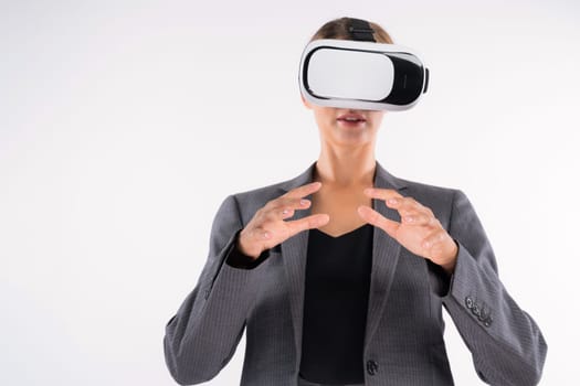 Business woman holding something while wearing VR goggle and standing at white background. Project manager with headset enter visual reality world program by using technology innovation. Contraption.