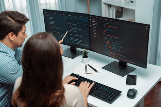 Team skilled developers program coding discussing creative website planning software project on two screen monitor's full stack data analyzing design at office with back side view concept. Postulate.