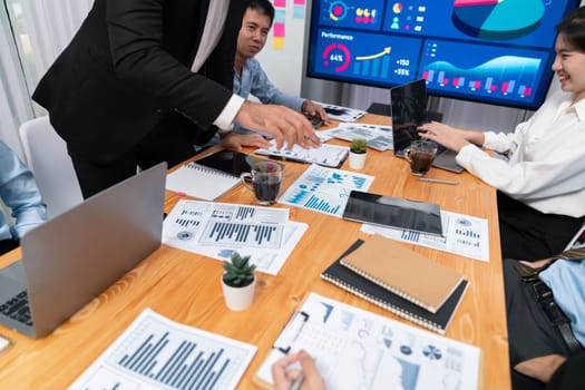 Diverse group of business analyst team analyzing financial data report. Finance data analysis chart and graph dashboard show on TV screen in meeting room for strategic marketing planning. Habiliment