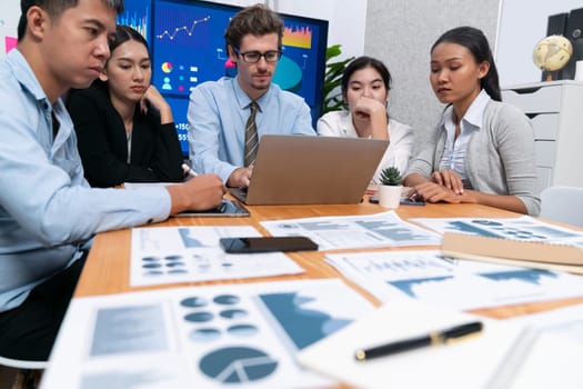 Diverse group of business analyst team analyzing financial data report. Finance data analysis chart and graph dashboard show on TV screen in meeting room for strategic marketing planning. Meticulous