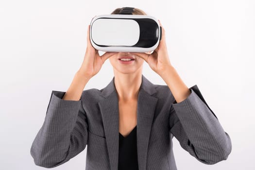 Skilled businesswoman looking at visual reality world by using VR glass while standing at background. Smart manager holding VR goggle to connect metaverse by using technology innovation. Contraption.