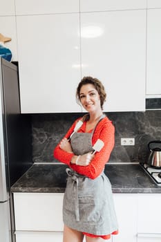 woman in an apron a cook stands in the kitchen near the refrigerator