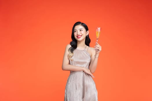 Young happy woman in shiny stylish dress looking away and smiling with champagne isolated