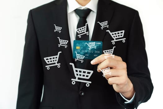 Elegant customer wear black suit and tie hold credit card, cashless technology, by left hand. Smart consumer use hologram graphic interface of e-commerce application platform around hands. Cybercash.