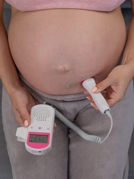 Close-up of a pregnant woman's belly using a home doppler. Normal baby heartbeat