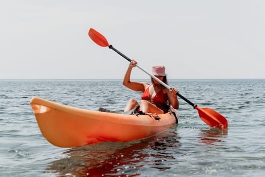 Happy smiling woman in kayak on ocean, paddling with wooden oar. Calm sea water and horizon in background