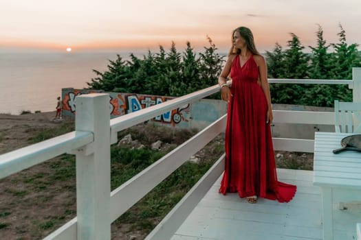 Woman sunset sea red dress, portrait happy beautiful sensual woman in a red long dress posing above the sea on sunset