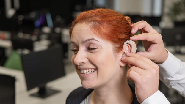 Man putting hearing aid on Caucasian red-haired woman