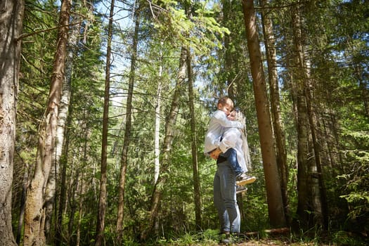 Funny mother with dreadlocks and fat boy happy walking in the forest on a sunny summer day