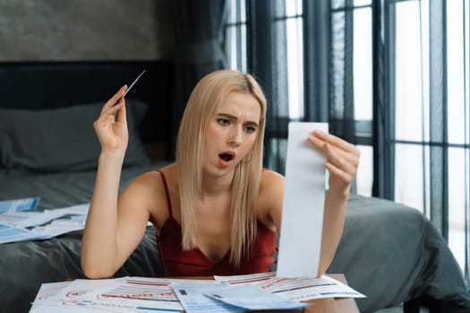 Stress worried young woman sit at table, as she pay bills online with credit card from financial debt problem, monthly expense and credit card debt. Over spending money lifestyle problem. Blithe