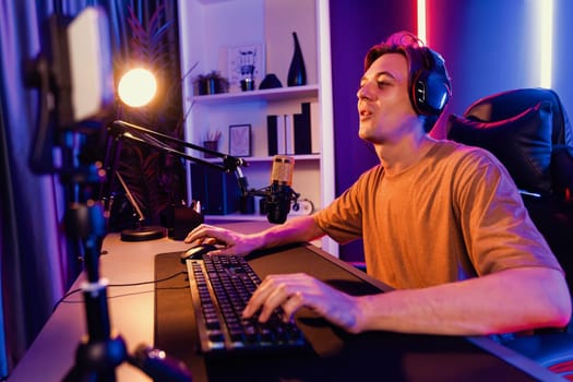 Host channel of gaming smart streamer playing online game to be winner, wearing headphone with viewers live steaming on media social online for selected team competition at neon light room. Pecuniary.