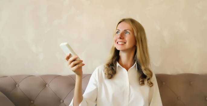 Happy smiling caucasian young woman turns on the air conditioner or TV using the remote control in living room at home