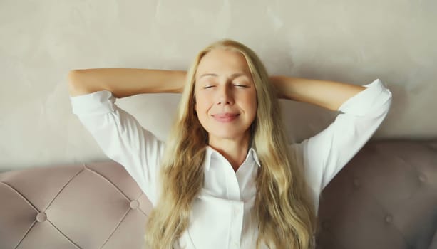 Happy relaxed middle aged woman enjoying at home, satisfied girl sitting on the couch in living room