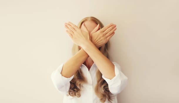 Upset woman shows stop, no or enough sign with palm of hand, refusal gesture, domestic violence.