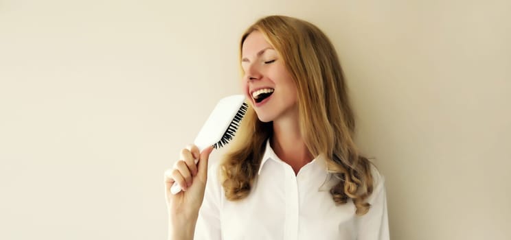 Portrait of happy cheerful woman having fun sings with hair comb and laughing ready to go outside in high spirits
