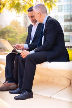 Two trusted business colleagues dressed in formal attire with a computer in hand observing the results of the work done