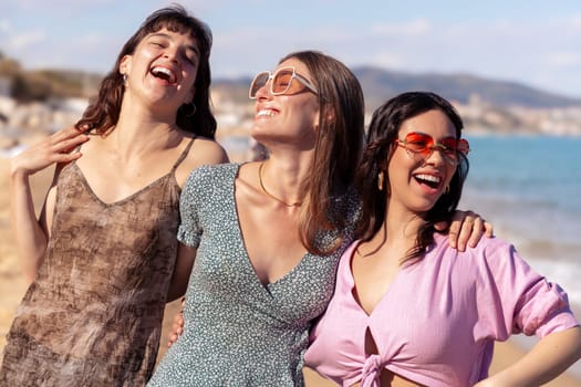 Cheerful multiethnic friends with sunglasses happy on vacation on the beach, looking at the camera.