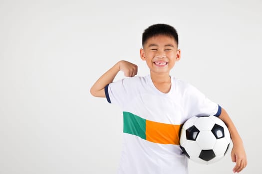 Portrait Asian smiling young boy kids holding soccer ball and power strong studio shot isolated white background, cute child playing football show muscle, sport hobby for kids, leisure games