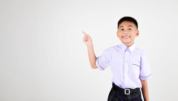 Portrait smile Asian little boy primary posing point finger to side away studio isolated white background, happy cute man kid wear school uniform plaid innocence and curiosity, back to school concept