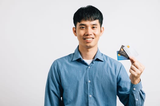 Portrait Asian smiling young man holding two debit credit cards in his hand studio shot isolated white background, Happy lifestyle men person is proud of his financial situation