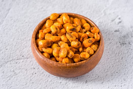 Roasted corn nuts with sauce in wooden bowl on white stone table