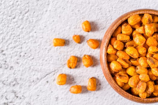 Roasted corn nuts with sauce in wooden bowl on white stone table