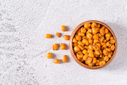 Roasted corn nuts with sauce in wooden bowl on white stone table