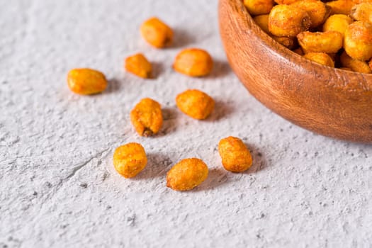 Roasted corn nuts with sauce in wooden bowl on white stone table