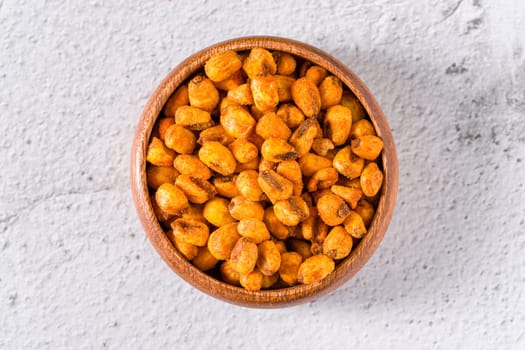 Roasted corn nuts with sauce in wooden bowl on white stone table