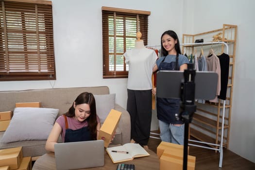 Lesbian couple managing an online live selling business from home, showcasing fashion products and engaging with customers.