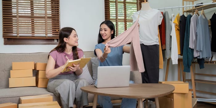 Lesbian couple working together on their online clothing business, packing orders and managing inventory from home.