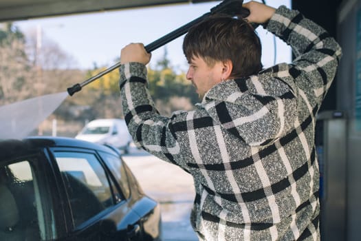 Cleaning car using active foam. Man washing his car on self car-washing