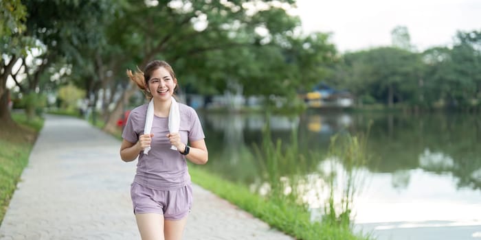 A young woman jogging along a lakeside path in the morning, enjoying her exercise routine in a serene park setting.