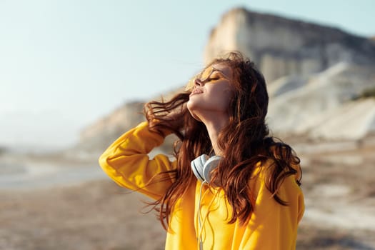 empowered woman admiring majestic mountain views in vibrant yellow sweatshirt